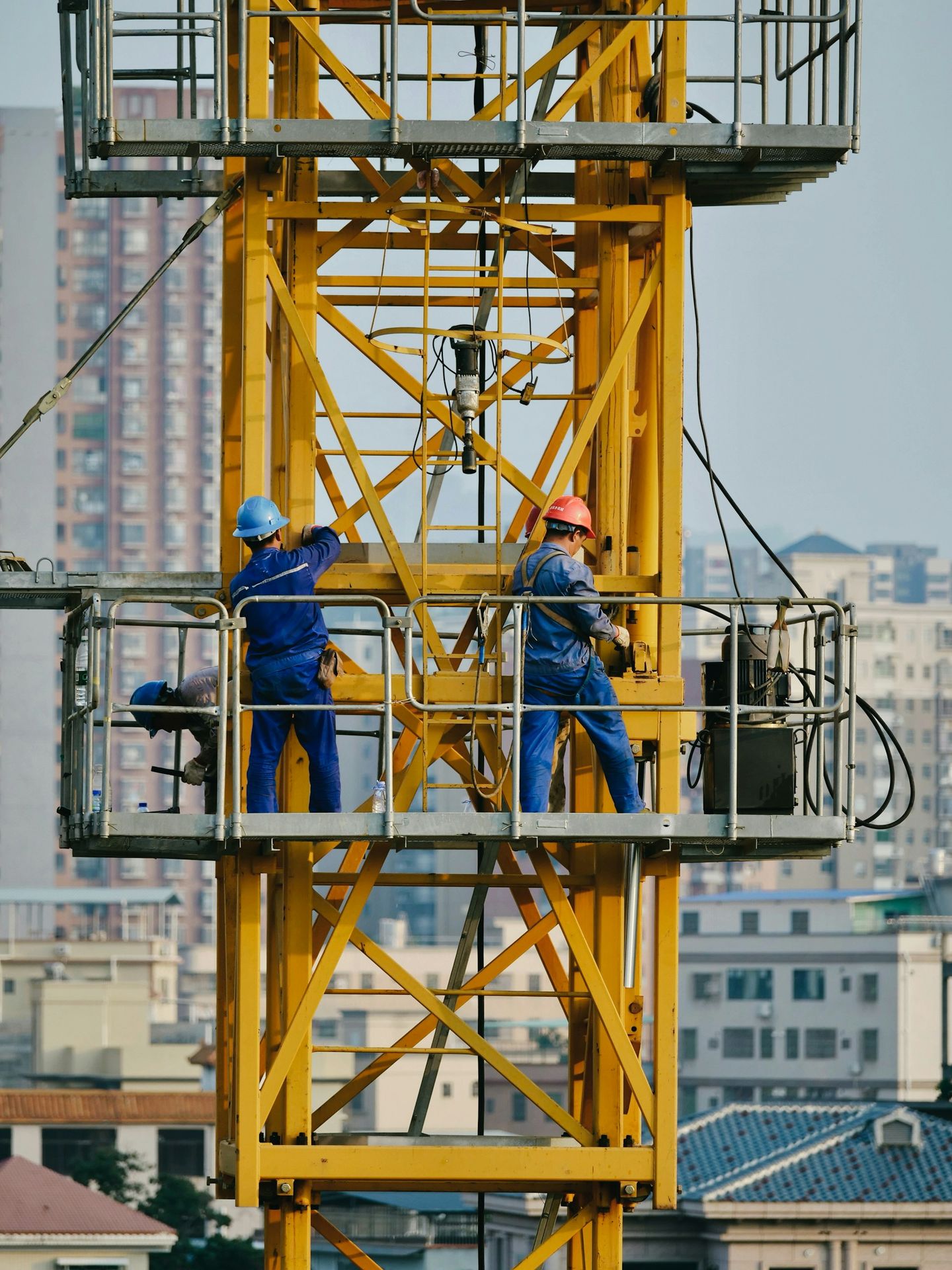 Construction workers working on a yellow crane.